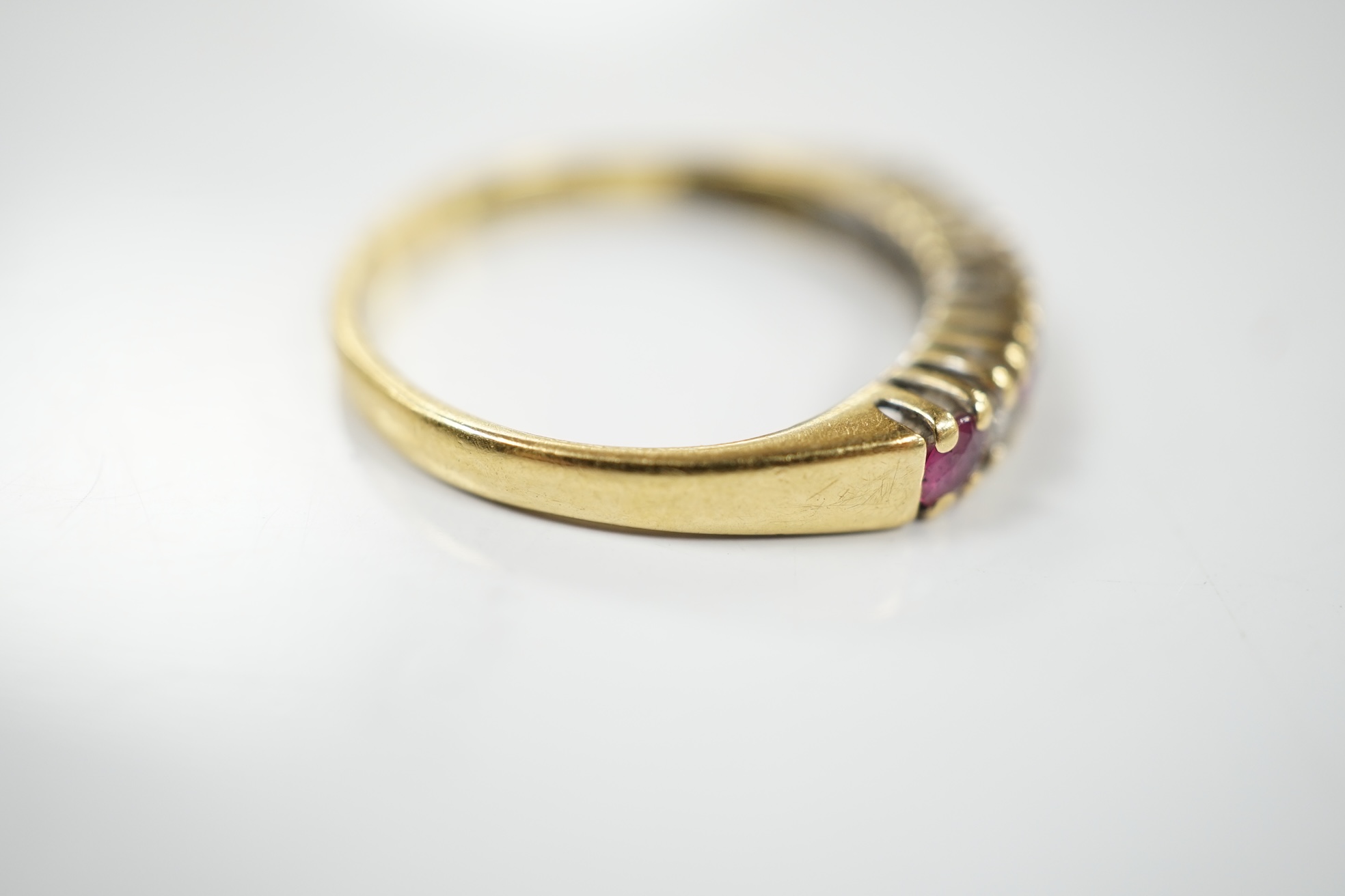 A modern 18ct gold, four stone ruby and three stone diamond set half hoop ring, size P, gross weight 2.8 grams. Condition - fair